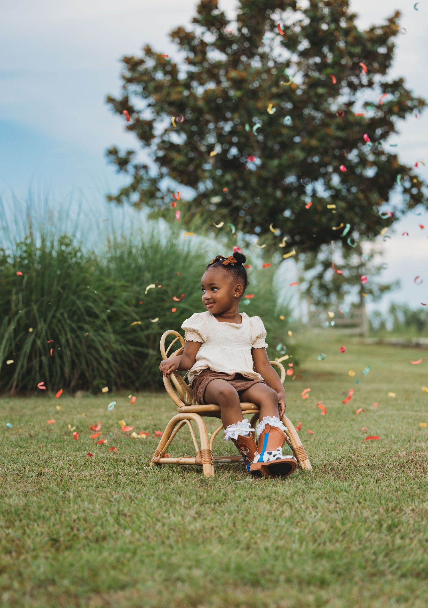 Child riding wooden rocking horse with confetti floating in the air outdoors.