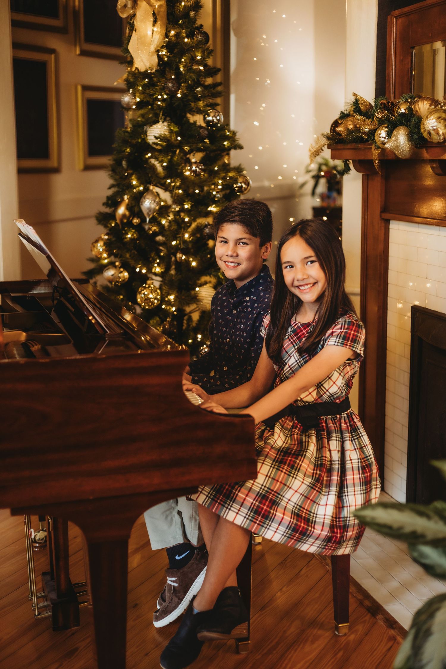 Children playing and laughing on wooden furniture near decorated Christmas trees.