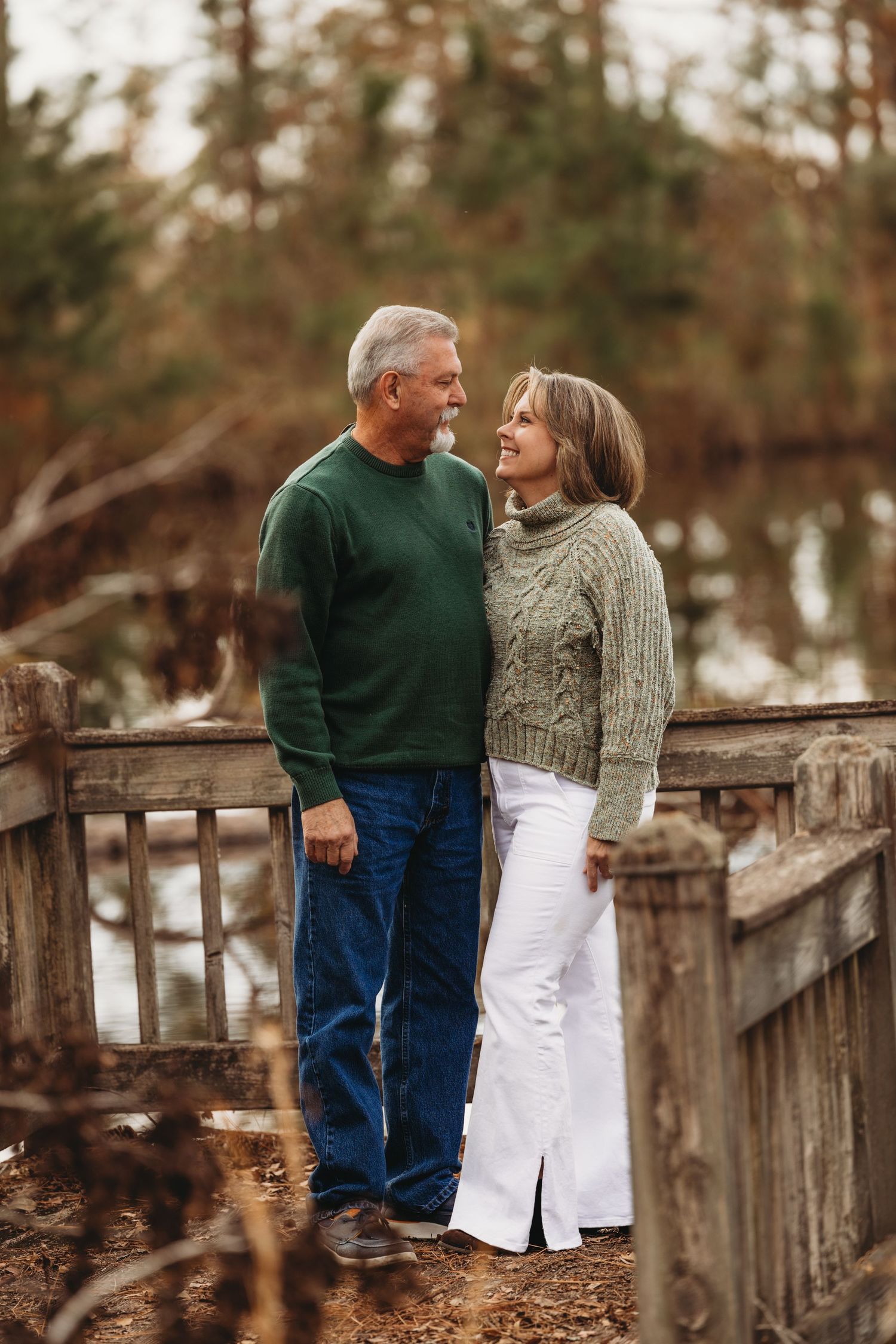 Couple sharing a tender moment on a rustic wooden bridge in autumn.