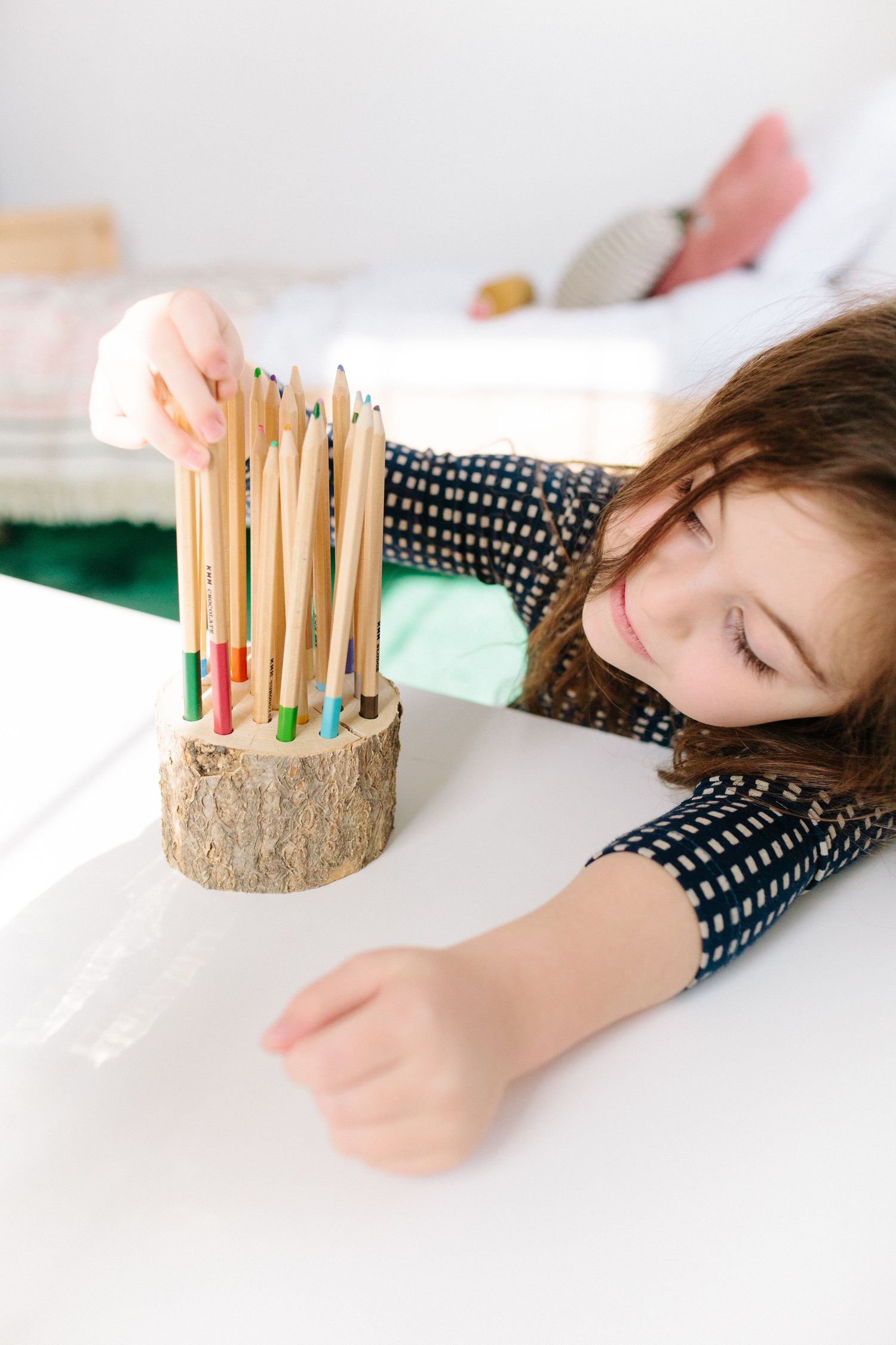 little girl sorting colored pencils at a desk