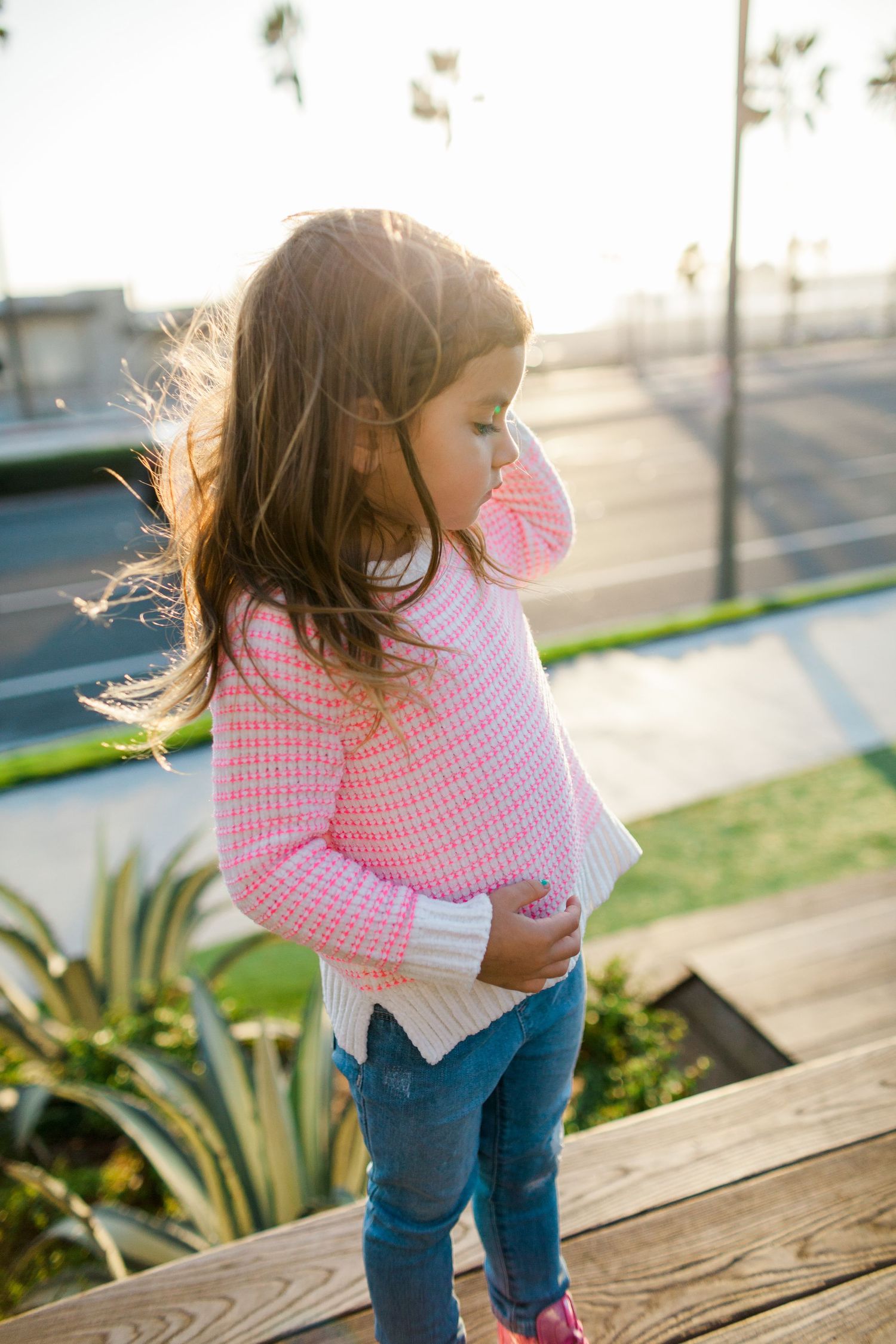 little girl modeling pink sweater with golden light behind her
