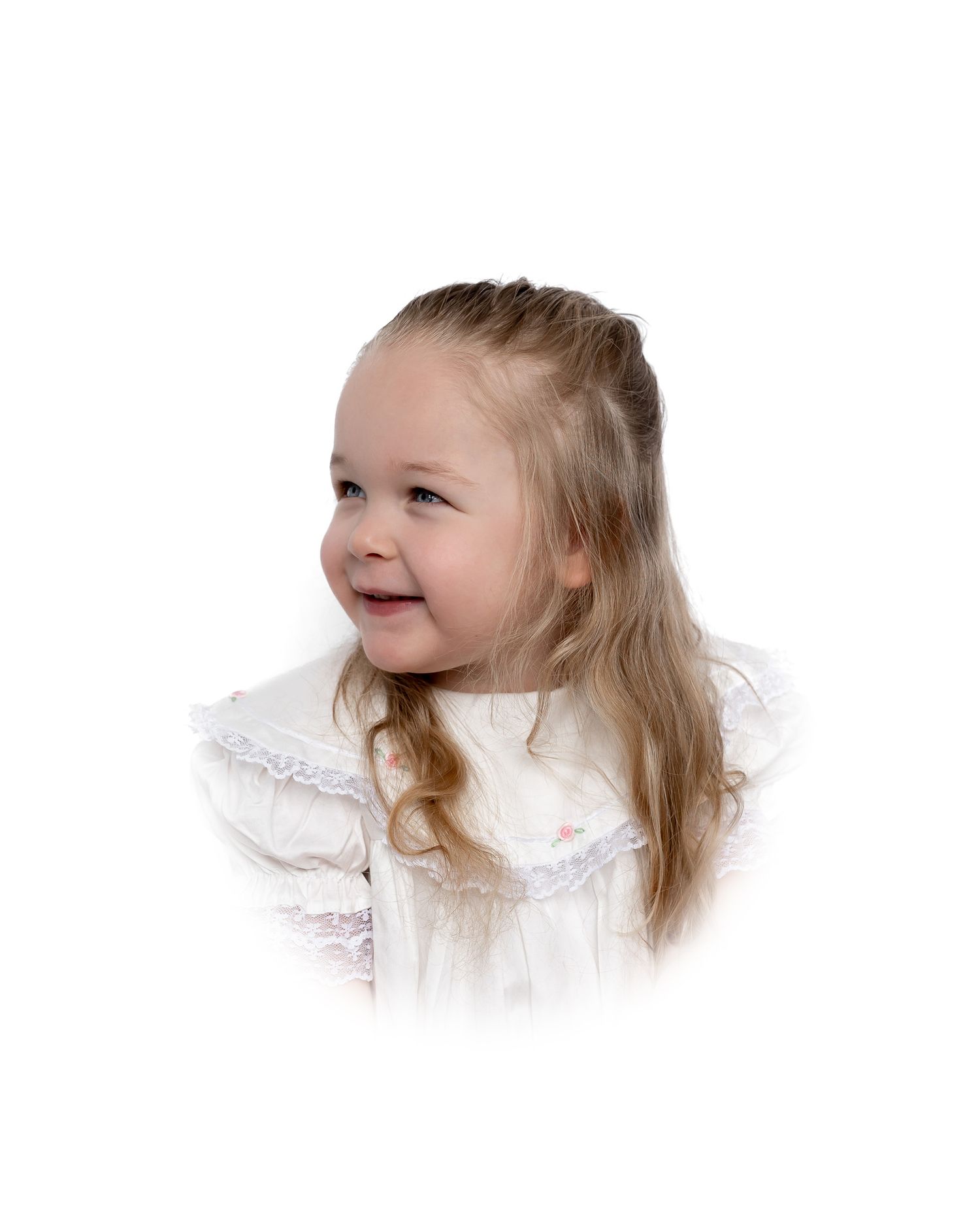 A young child with long blonde hair wearing a white dress smiles joyfully against a white background.