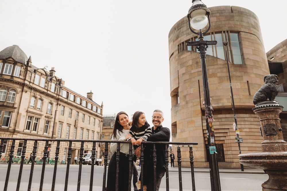 A group of people stand together on a stone staircase outside a historic building in Edinburgh.