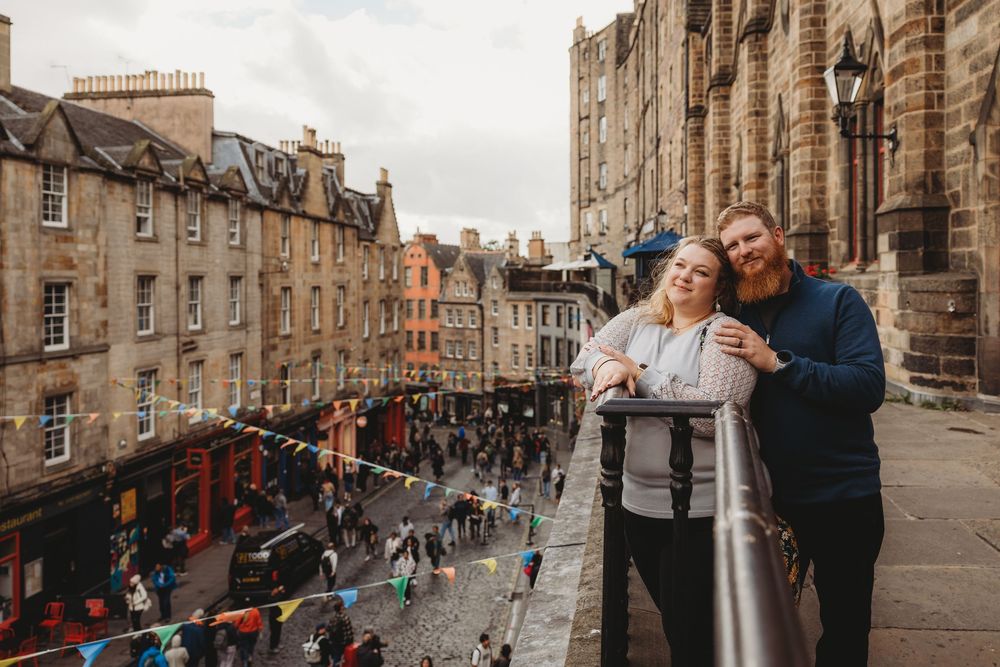 Couple exploring historic cobblestone streets and stone buildings in Edinburgh's Royal Mile during sunset.