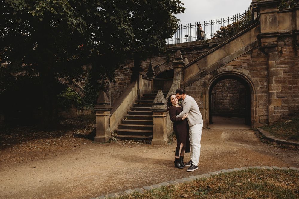 A romantic couple embraces on stone steps at a historic estate during a wedding photo session.