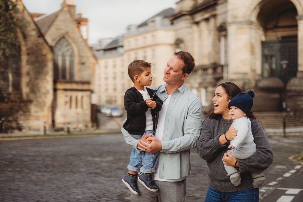 A father and son share playful moments together in a series of outdoor photos against historic architecture.