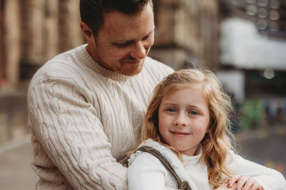 A parent and child share a tender moment together while wearing cozy cream-colored sweaters.