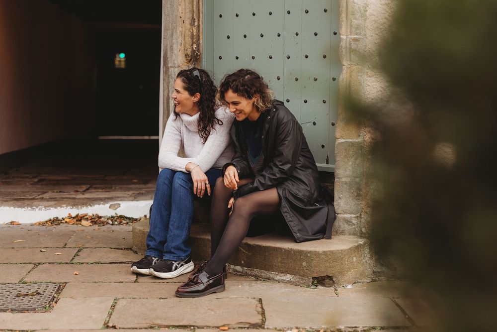 Two people sitting close together on outdoor steps sharing an intimate conversation in casual attire.