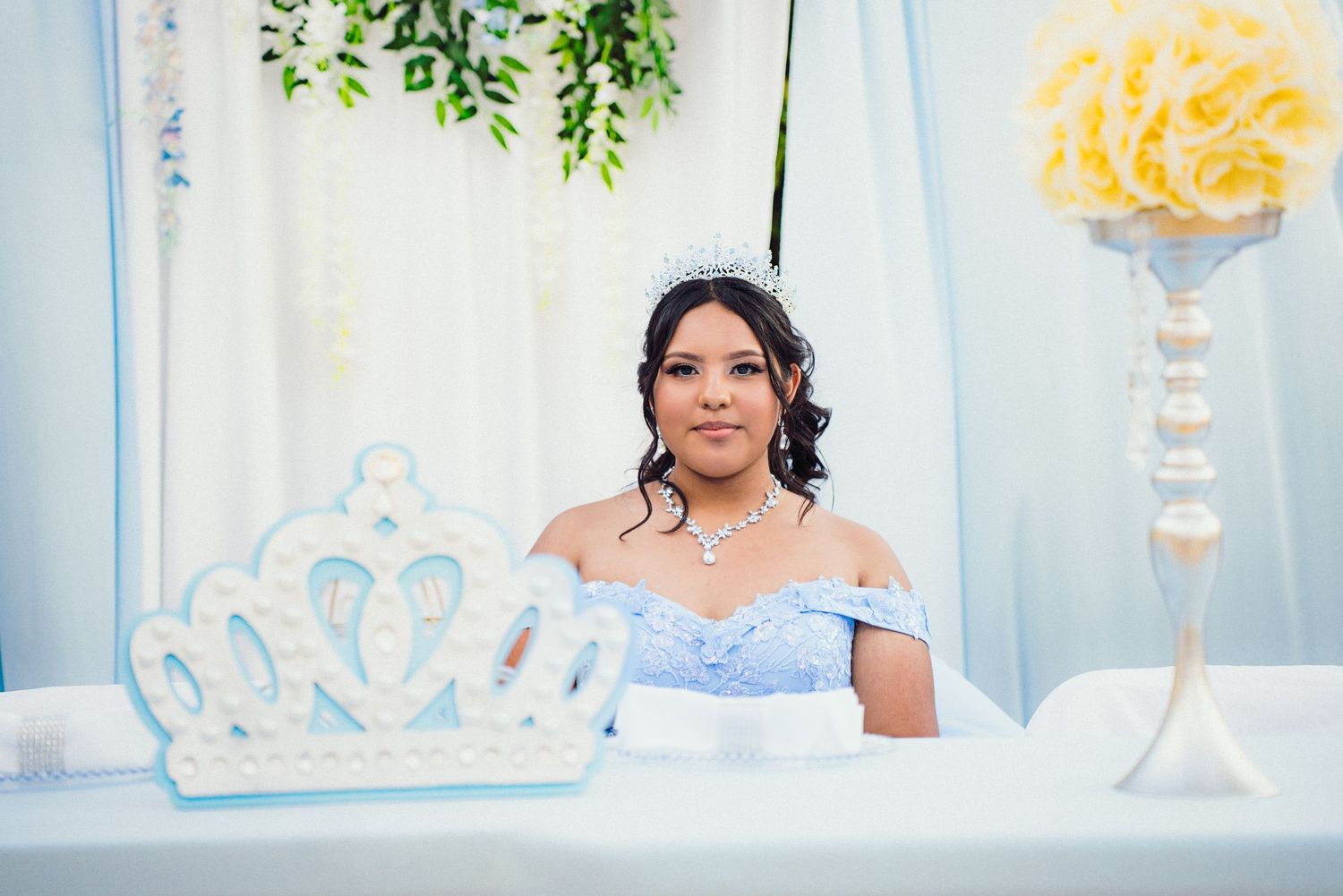 A bride and groom share their first dance at a wedding reception with blue and white decor in the background.