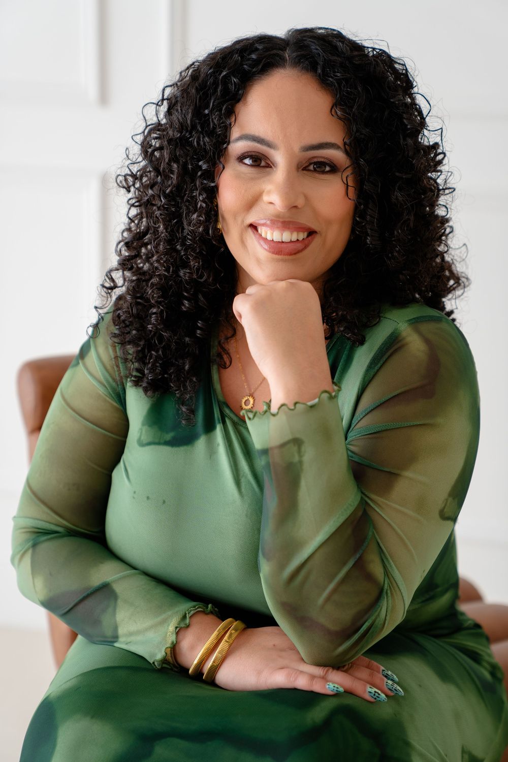 Lifestyle portrait series showing a person in a green sweater posing against a white background with curly hair.