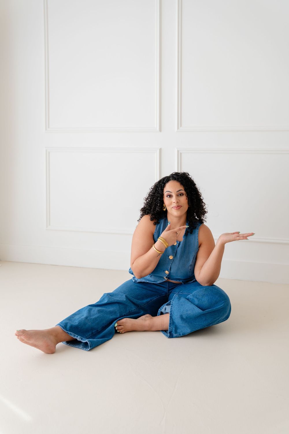 Casual fashion portraits of a person in denim overalls lounging on a white floor in various relaxed poses.