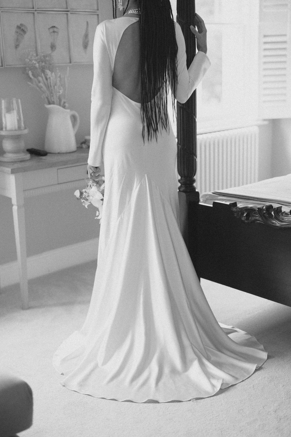 Back view of an elegant white wedding dress with a flowing train on a carpeted floor.