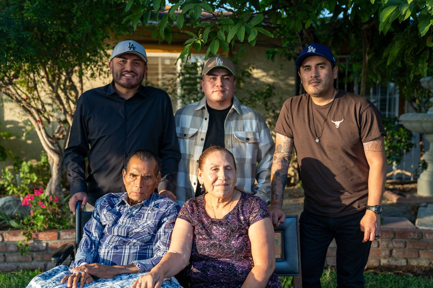 People sitting together on outdoor furniture in a garden setting during evening light.