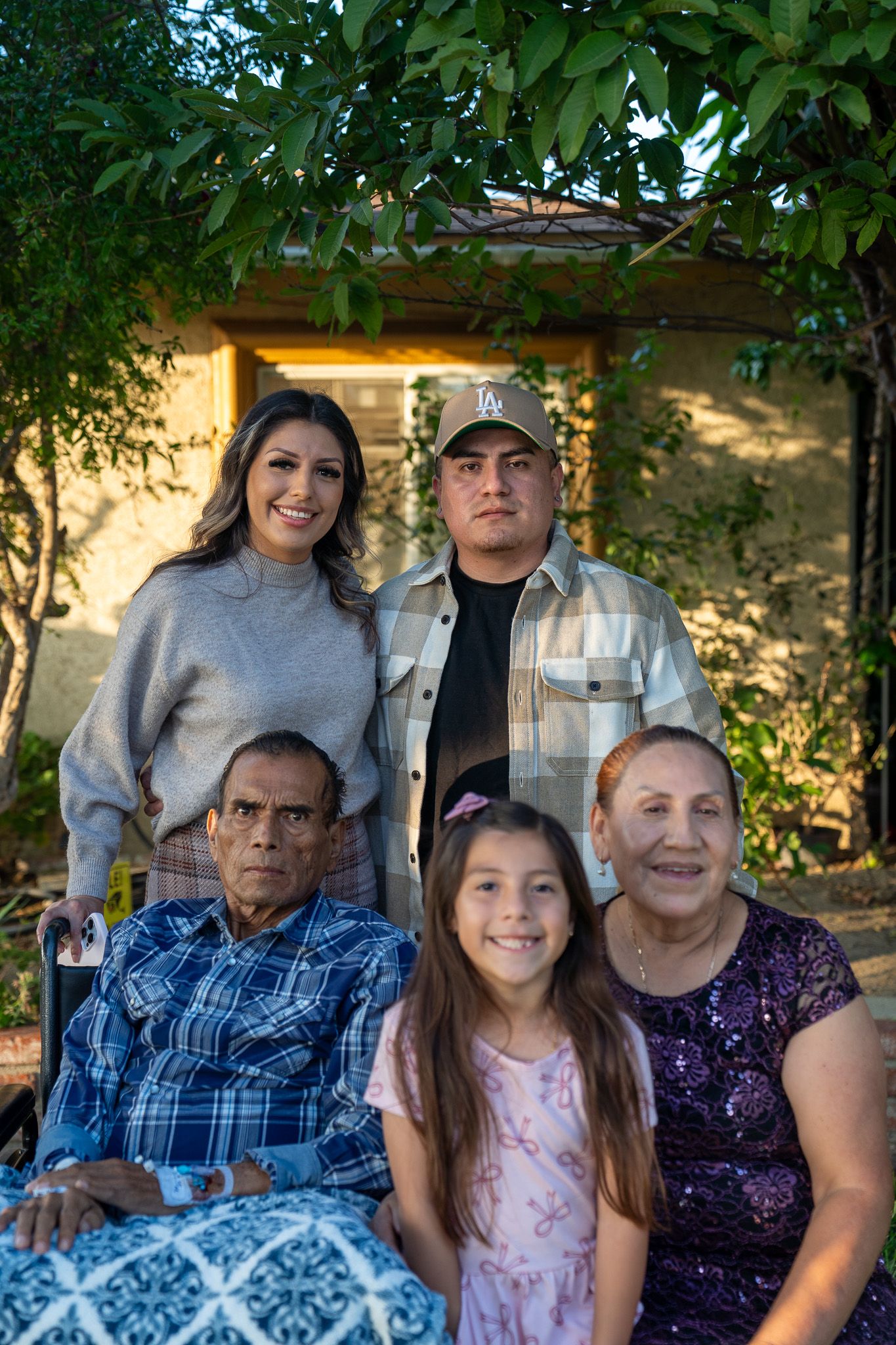 Multi-generational family photo taken outside with lush greenery and natural lighting.