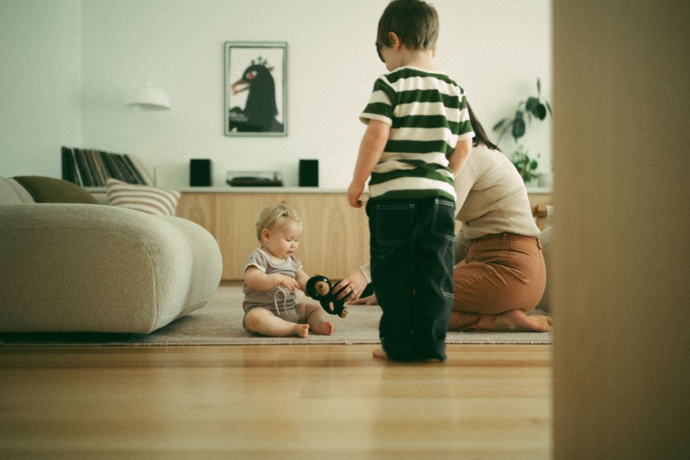 Children playing together on hardwood floor in living room with modern furniture and decor.