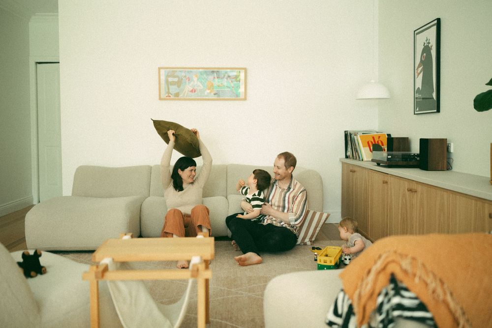 Two people relax in a cozy living room with retro decor and soft lighting while having a conversation.