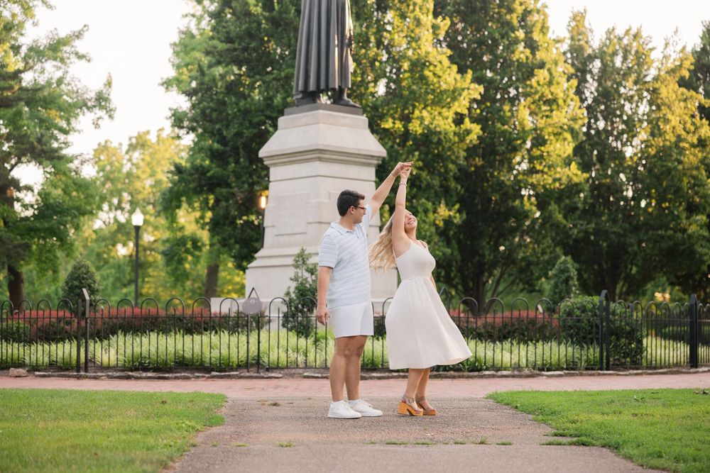 A couple shares a romantic moment in a garden setting with ornate pillars and lush greenery at sunset. Schiller Park Engagement Session