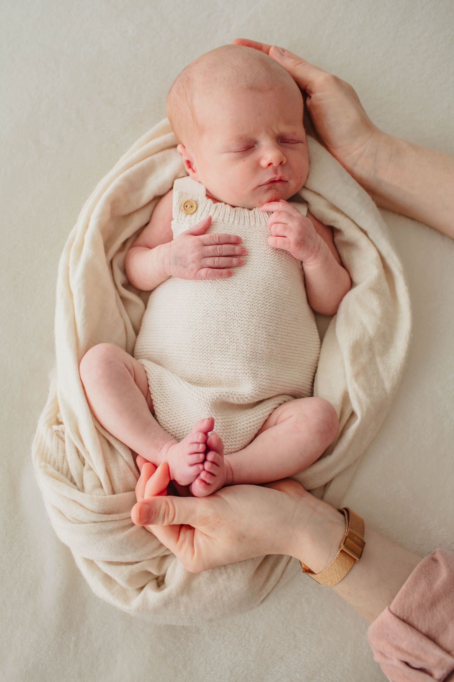 A black and white photo series shows a sleeping baby in different positions on white bedding.