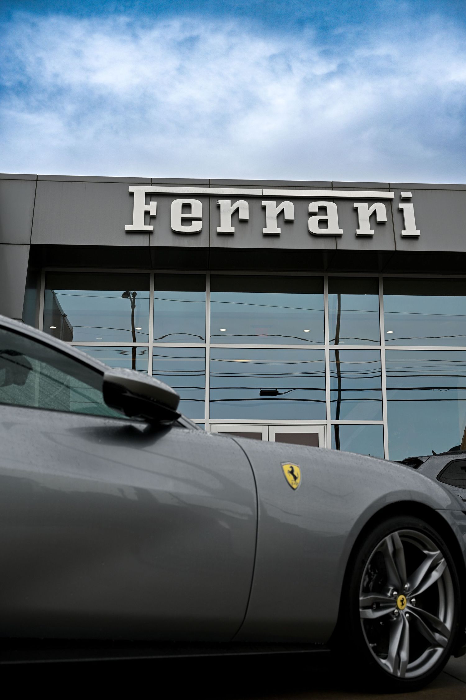 A sleek gray Ferrari sports car shown in a series of close-up detail shots against a dealership backdrop.