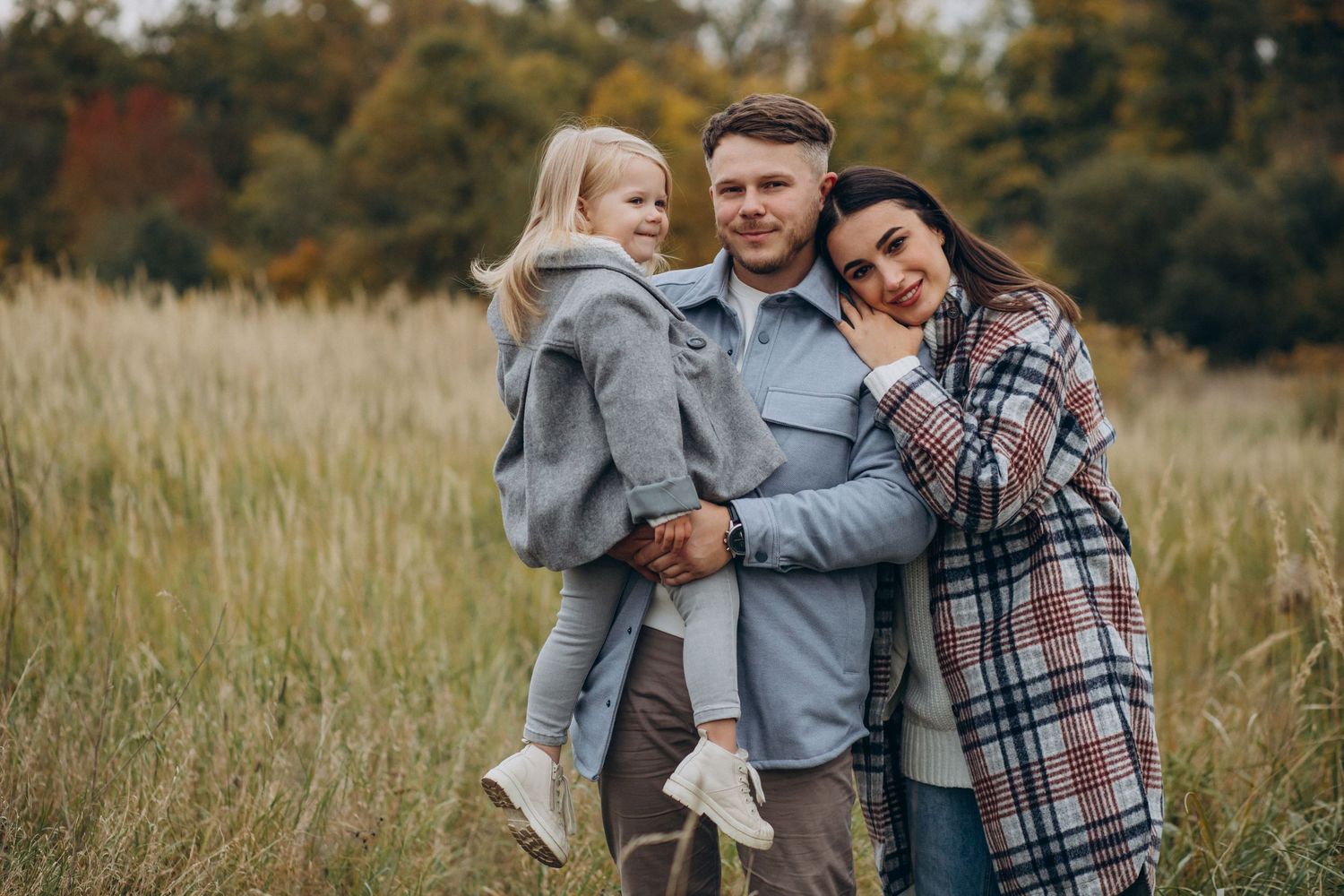 A couple shares tender moments in a field of tall grass during an autumn photoshoot.