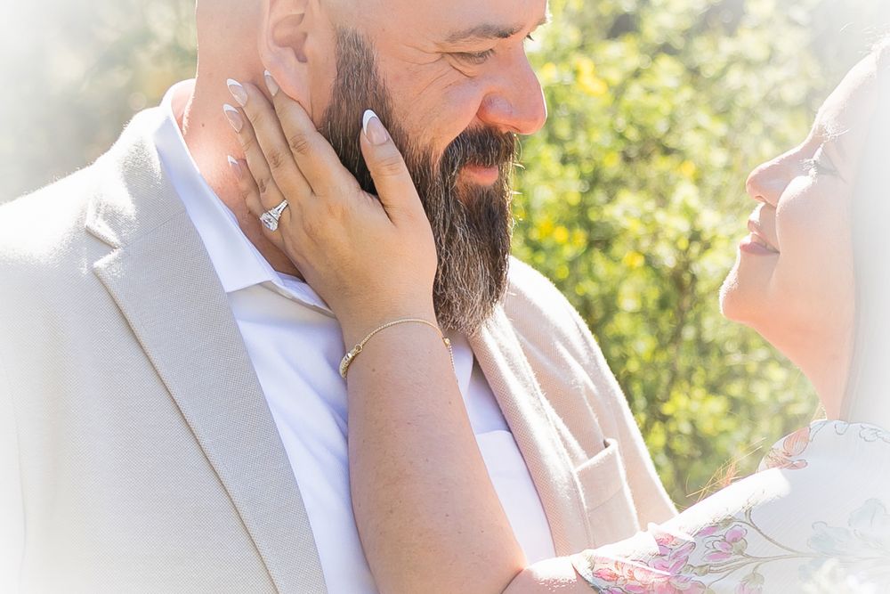 A tender moment between newlyweds in soft sunlight as they share an intimate embrace in their wedding attire.