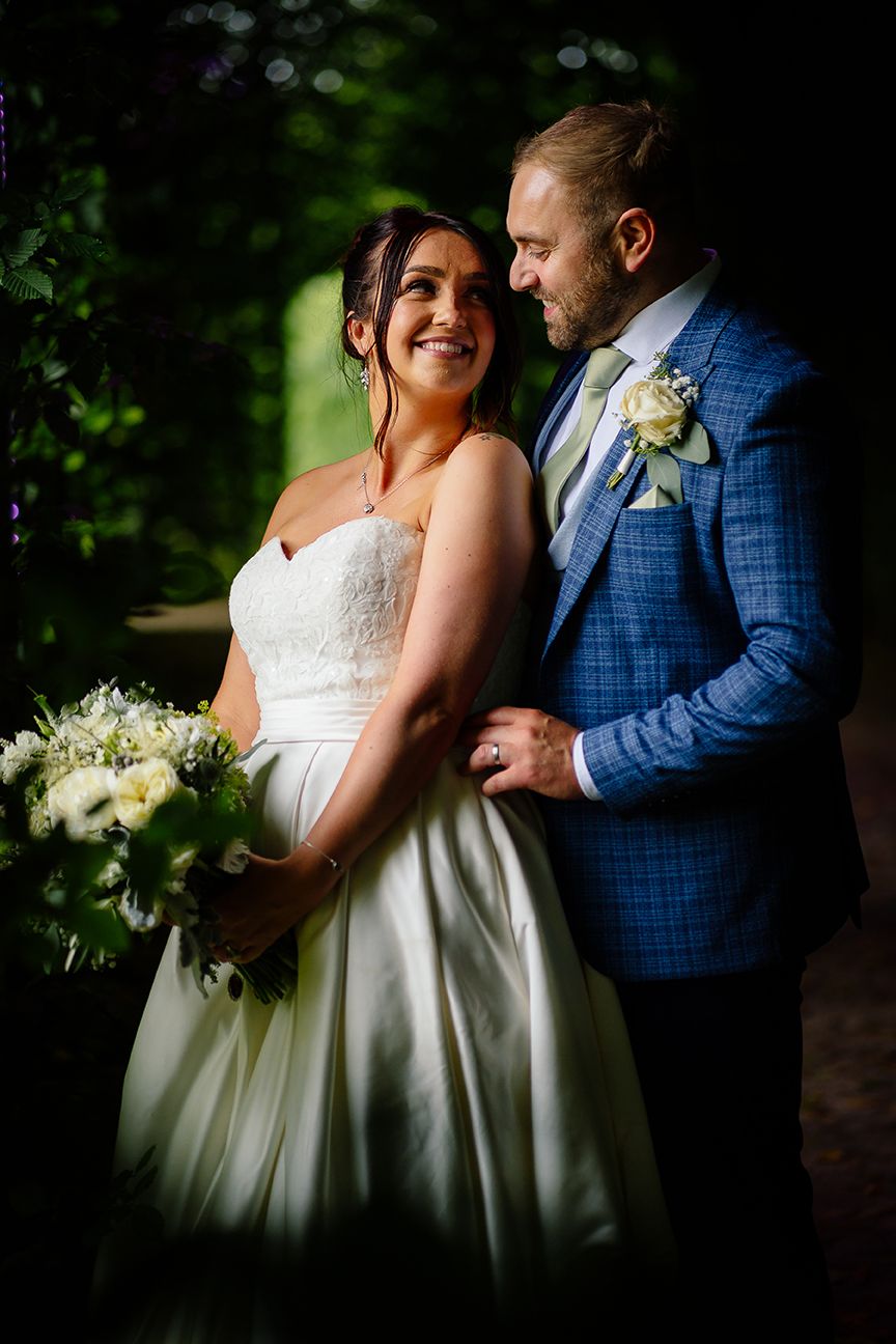 Romantic wedding couple shares intimate moments in a garden setting with lush greenery and natural lighting.