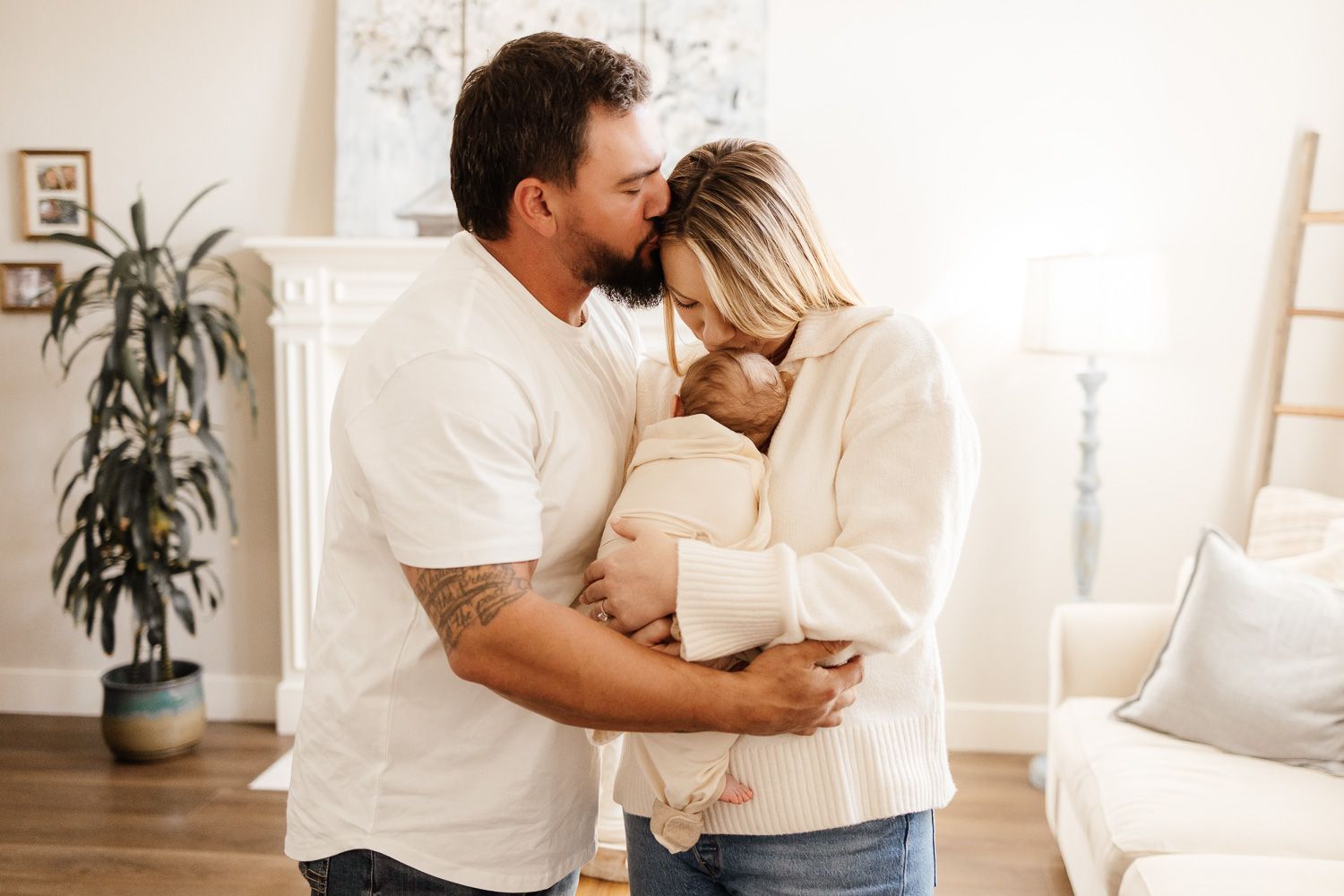 Parents share a tender kiss as they hold their baby in their living room