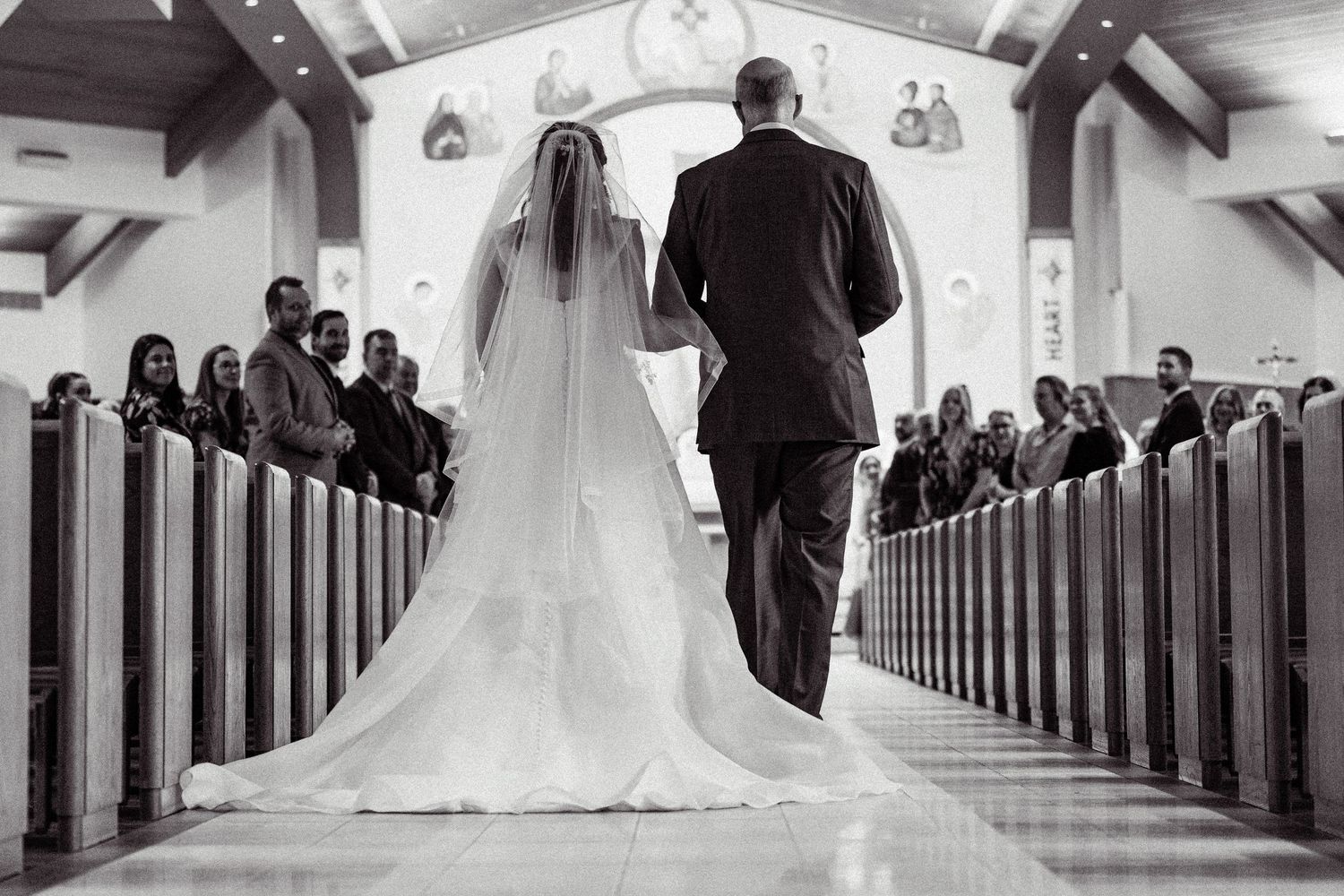 Bride and groom stand at church altar during wedding ceremony while guests observe from wooden pews.