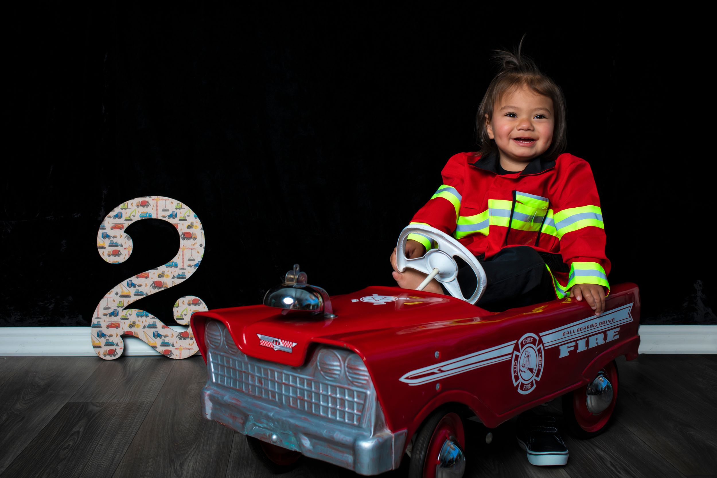 A collection of toy cars and ride-on vehicles arranged in a horizontal sequence showing playtime activities.