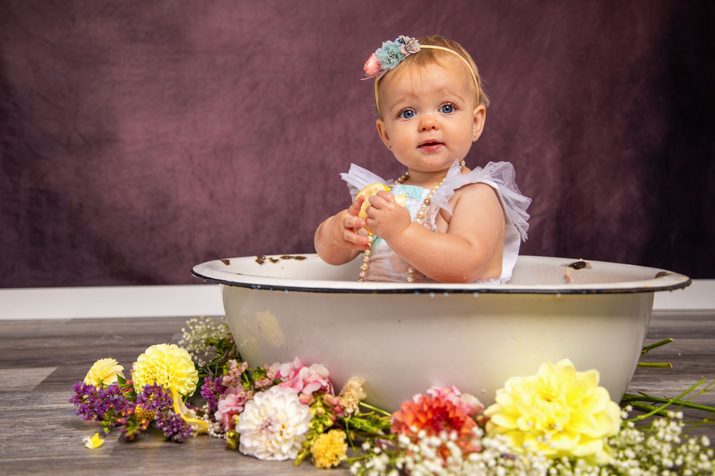 A series of connected photos showing a baby in a bathtub surrounded by colorful flowers for a milk bath photoshoot.