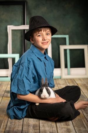 A boy in his hat holding a bunny.