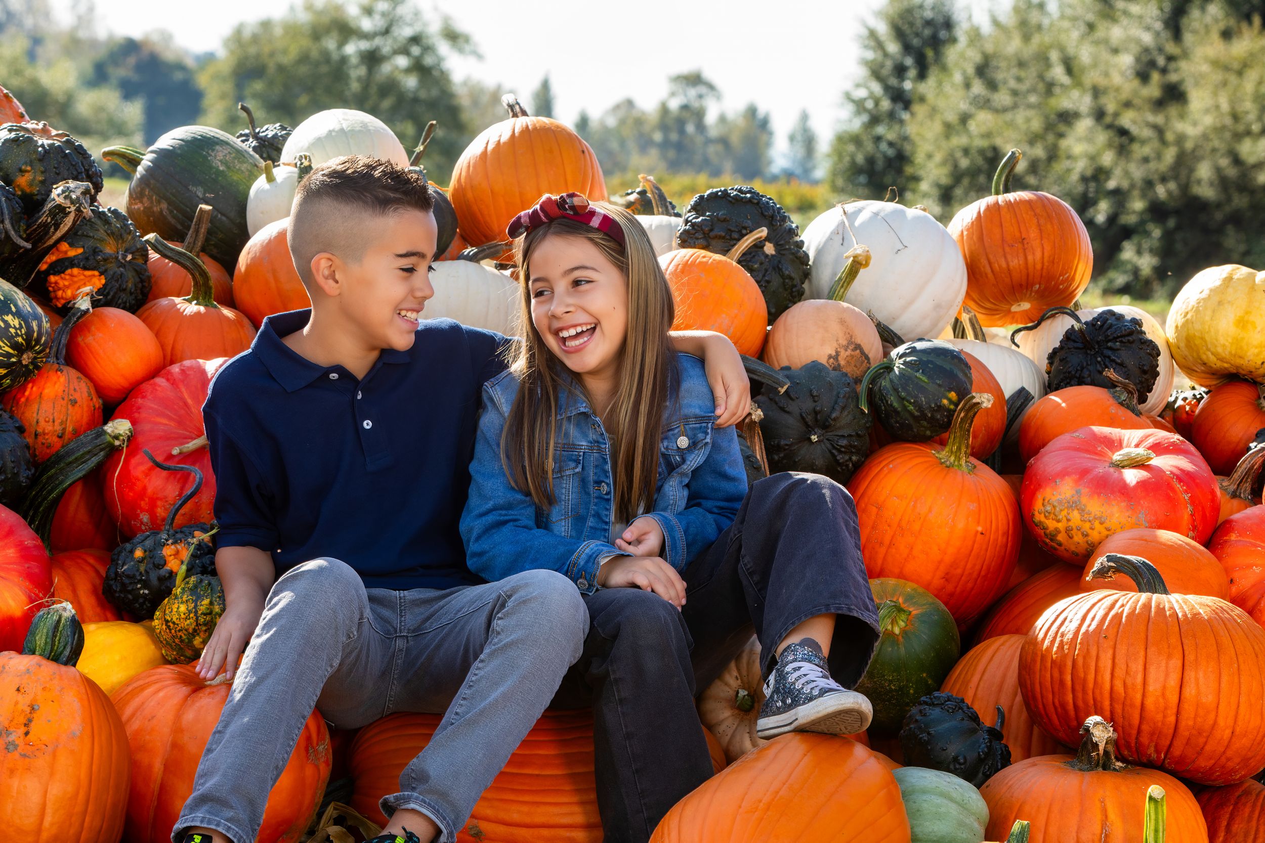 People enjoying a sunny autumn day at a pumpkin patch with bright orange pumpkins scattered around them.