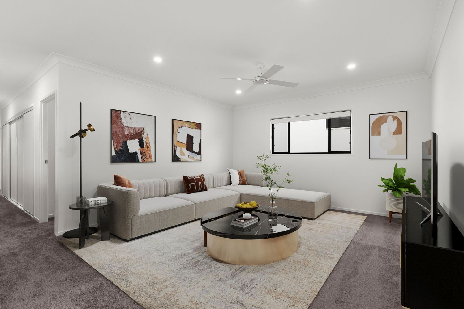 Modern living room with grey sectional sofa, round glass coffee table, ceiling fan, and dark carpet flooring.