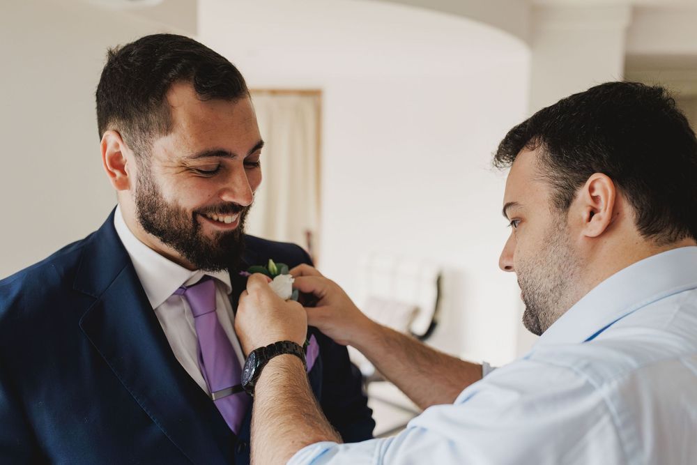 Best man helping the groom pin the boutonniere before the wedding ceremony.