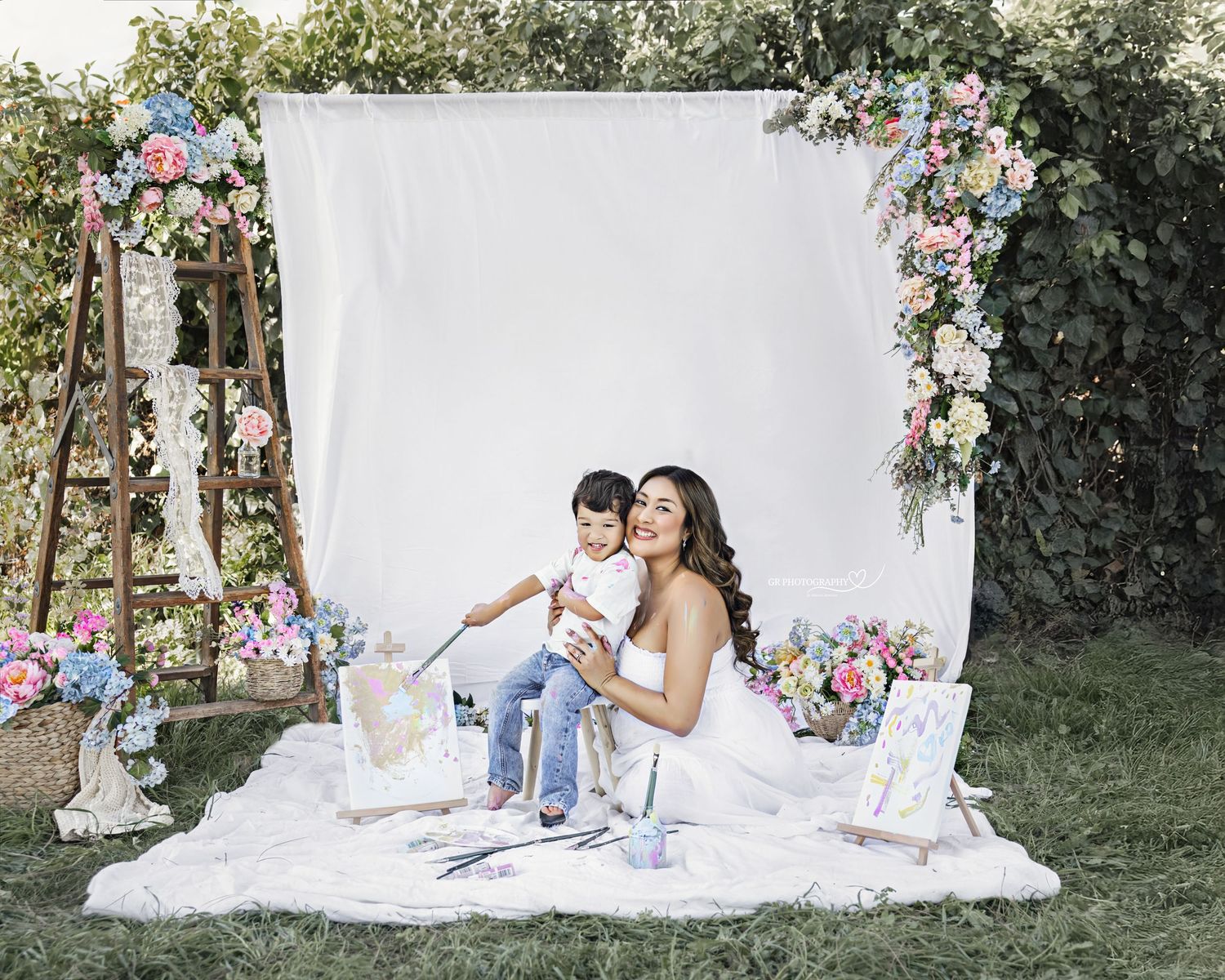 A romantic outdoor tea party setup with vintage decor, white linens, and floral arrangements in a garden setting.