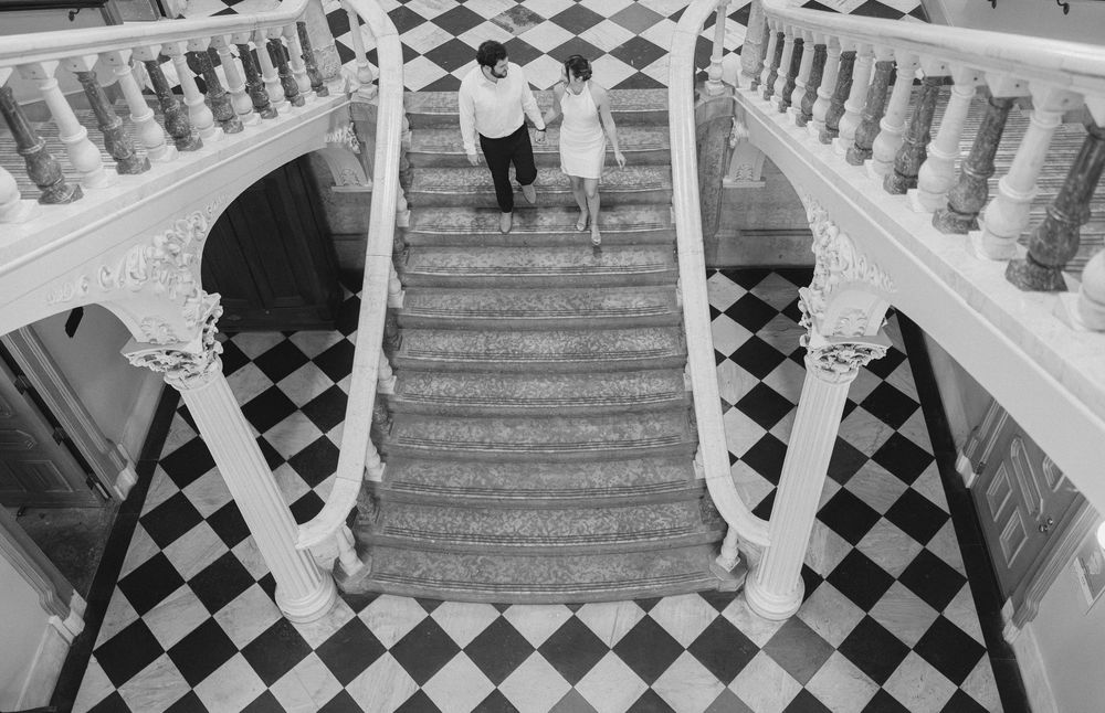Black and white checkered flooring creates a striking pattern in an elegant room with ornate wooden banisters. ohio state house engagement