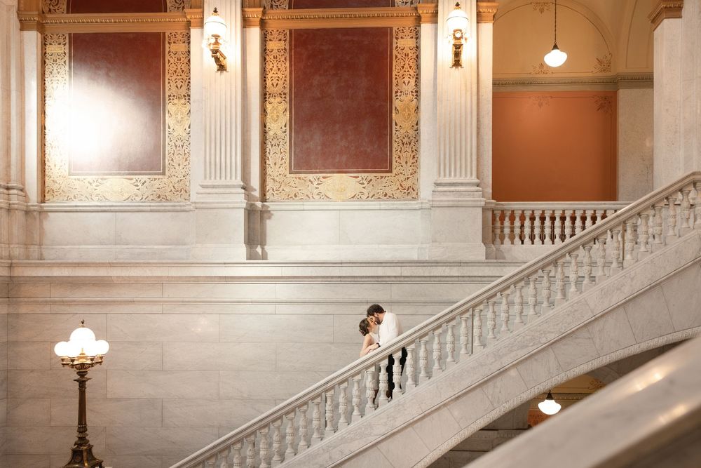 Elegant marble staircase and ornate architectural details in a grand historic building interior with warm lighting.