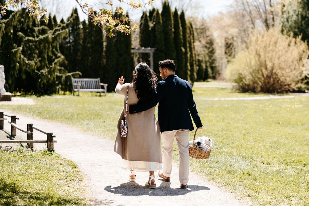 A couple walking through a sunny garden park carrying baskets on a spring afternoon.