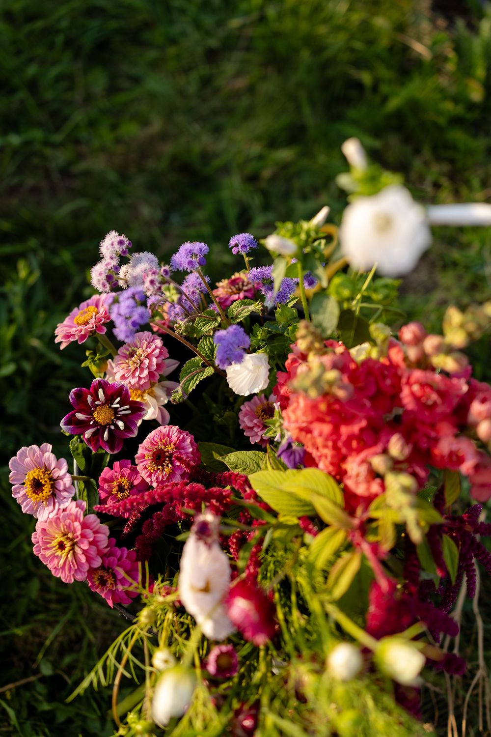 Vibrant floral arrangement featuring pink, purple, and red blooms with lush greenery in natural outdoor lighting.