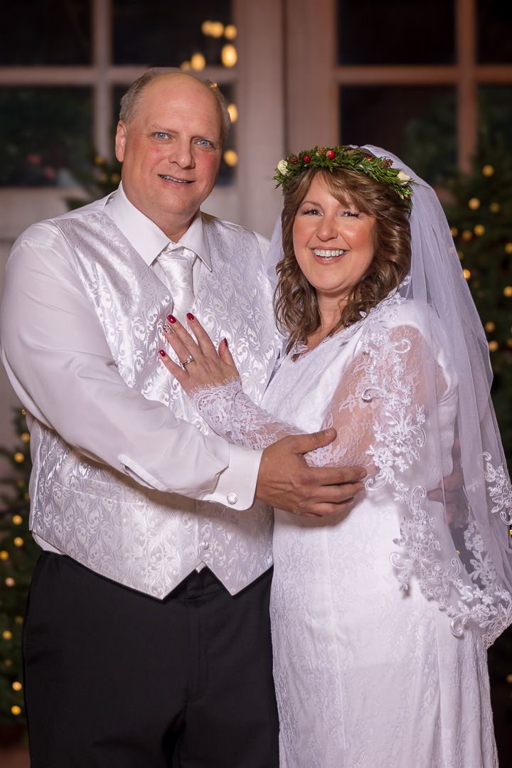 Frederick Maryland Wedding Photographer   A bride and groom in white formal attire share romantic moments with twinkling lights behind them.