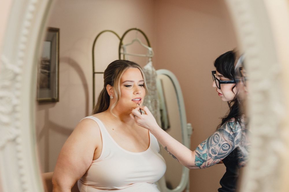 Makeup artist applies cosmetics to client's face during professional beauty session in natural lighting.