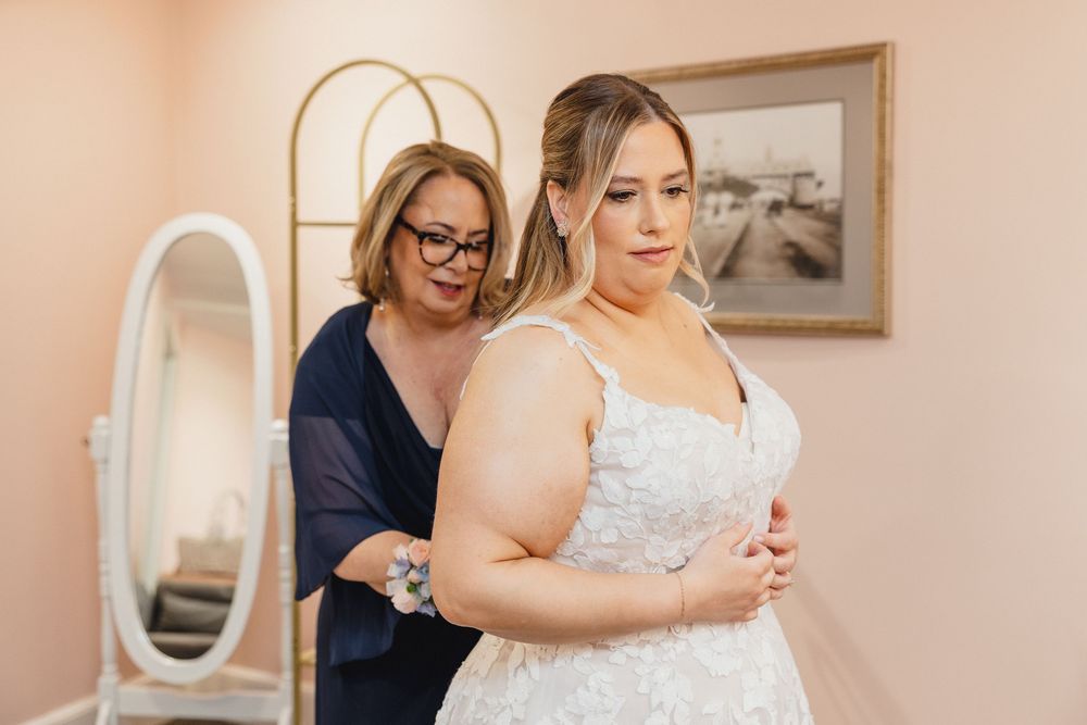 A series of wedding preparation photos showing someone in a white dress getting ready in a room with framed artwork.