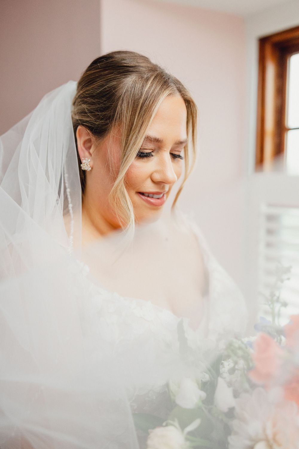 Close-up bridal portraits showing a delicate white veil and soft romantic lighting in an indoor setting.