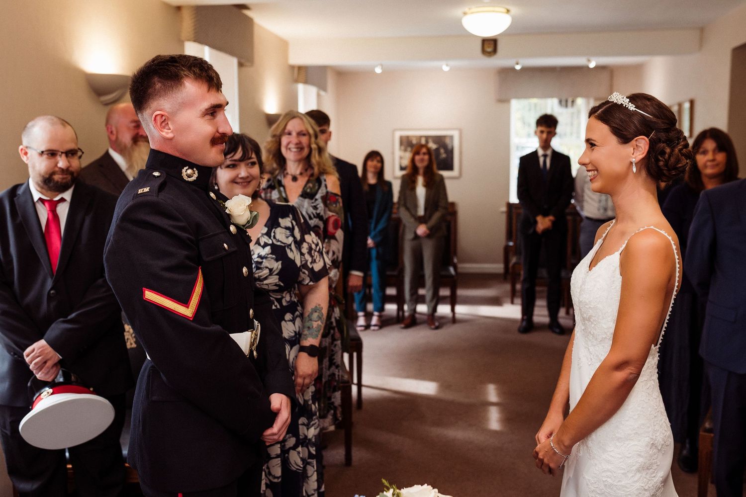 Wedding guests gather in an elegant indoor reception venue with warm lighting and formal attire.