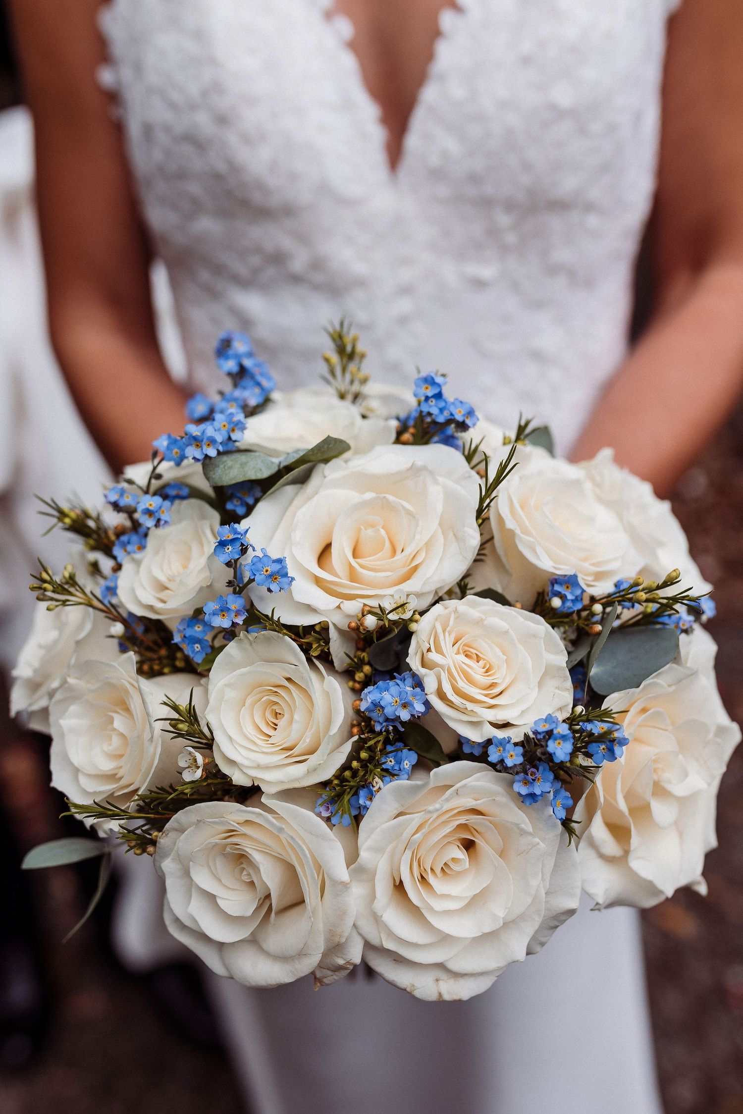 White roses and delicate blue forget-me-nots arranged in elegant bridal bouquets displayed in a row.