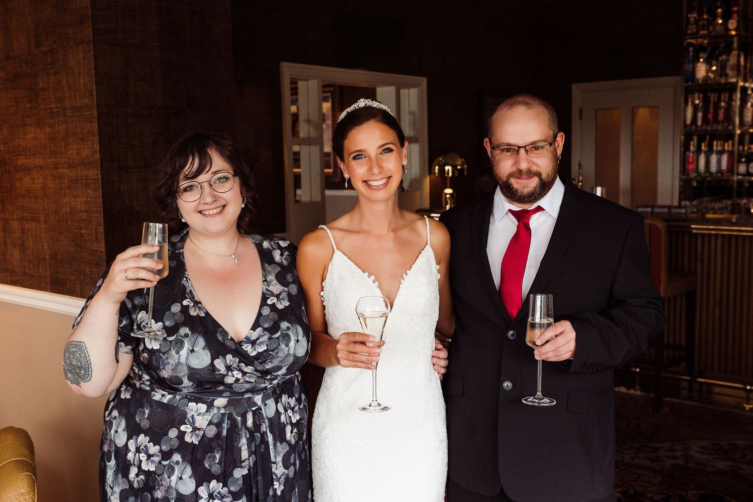 Group celebrating at an elegant indoor wedding reception with warm wood paneling.