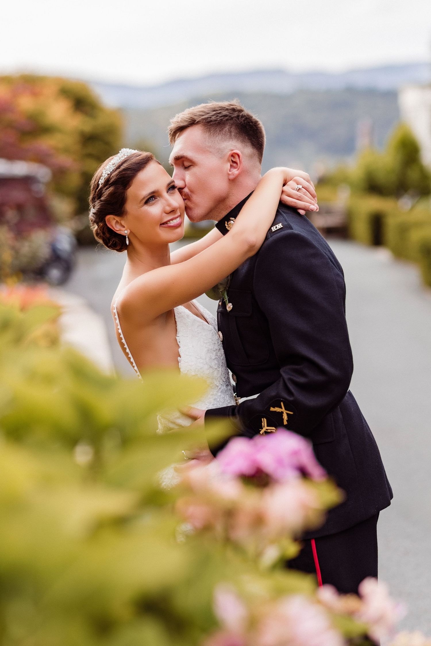 A romantic wedding photoshoot with a couple embracing against a scenic mountain backdrop.