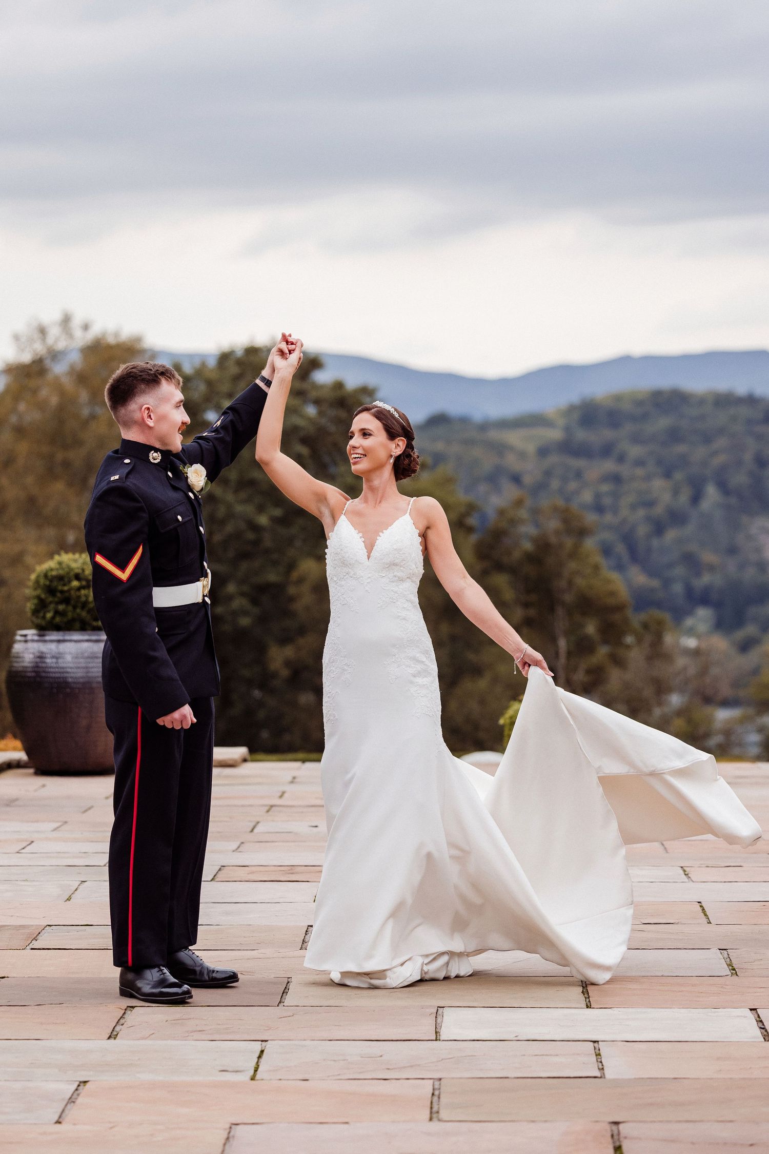 Wedding couple dancing and twirling on a stone patio with mountain views in the background.