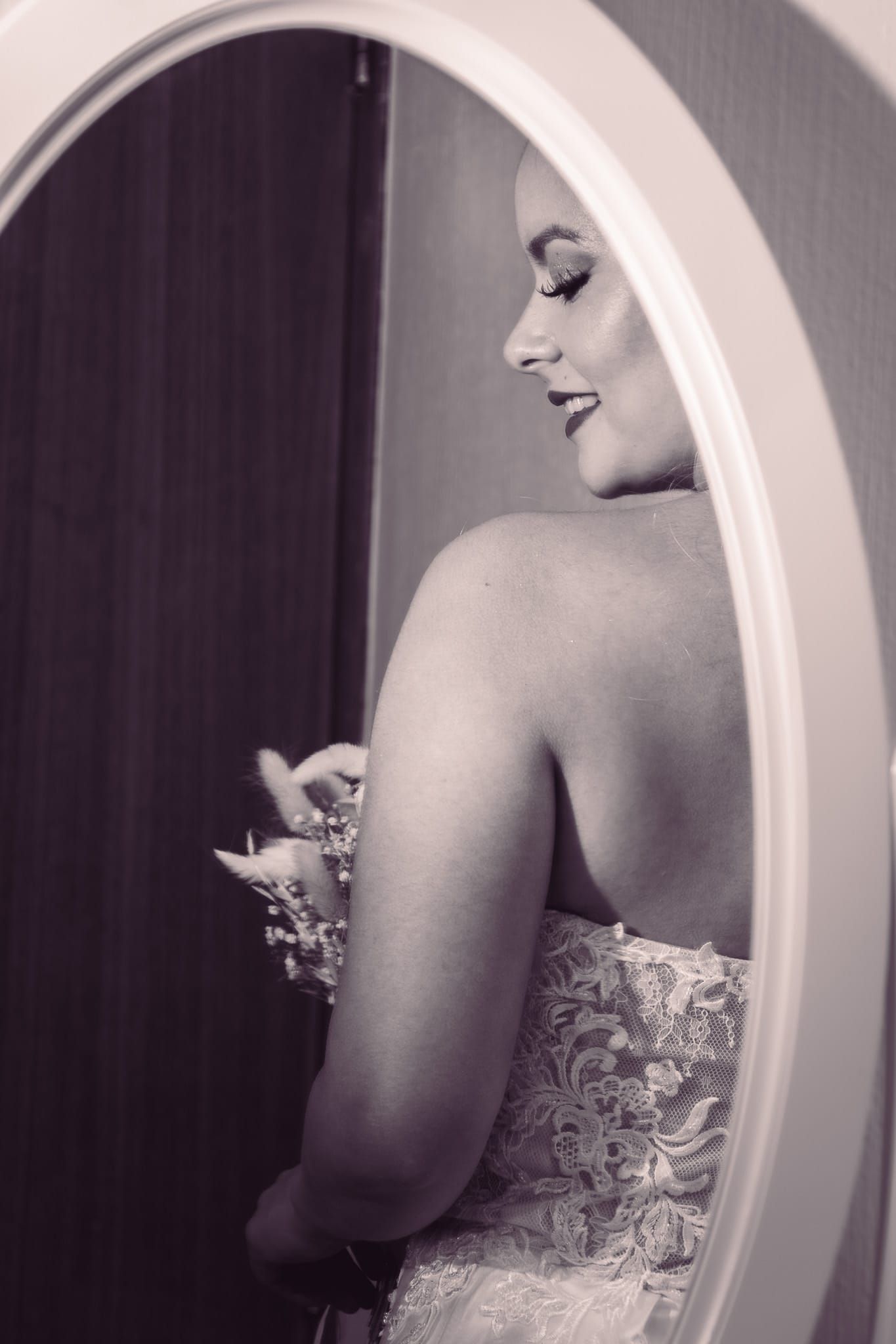 Reflejo artístico en espejo en blanco y negro mostrando detalles posteriores de vestido de novia.