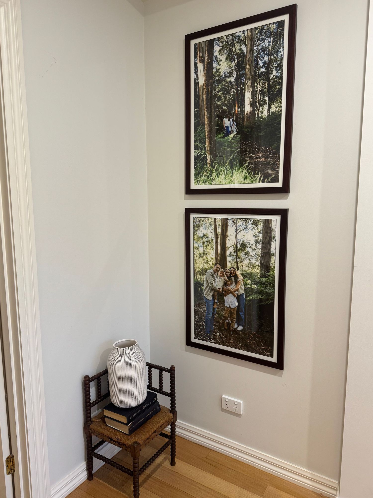 White room corner with black-framed artwork on walls, hardwood flooring, and minimal decor creating a clean aesthetic.